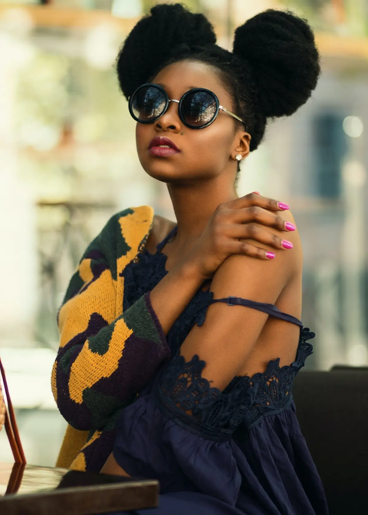 black woman with round sunglasses and space buns