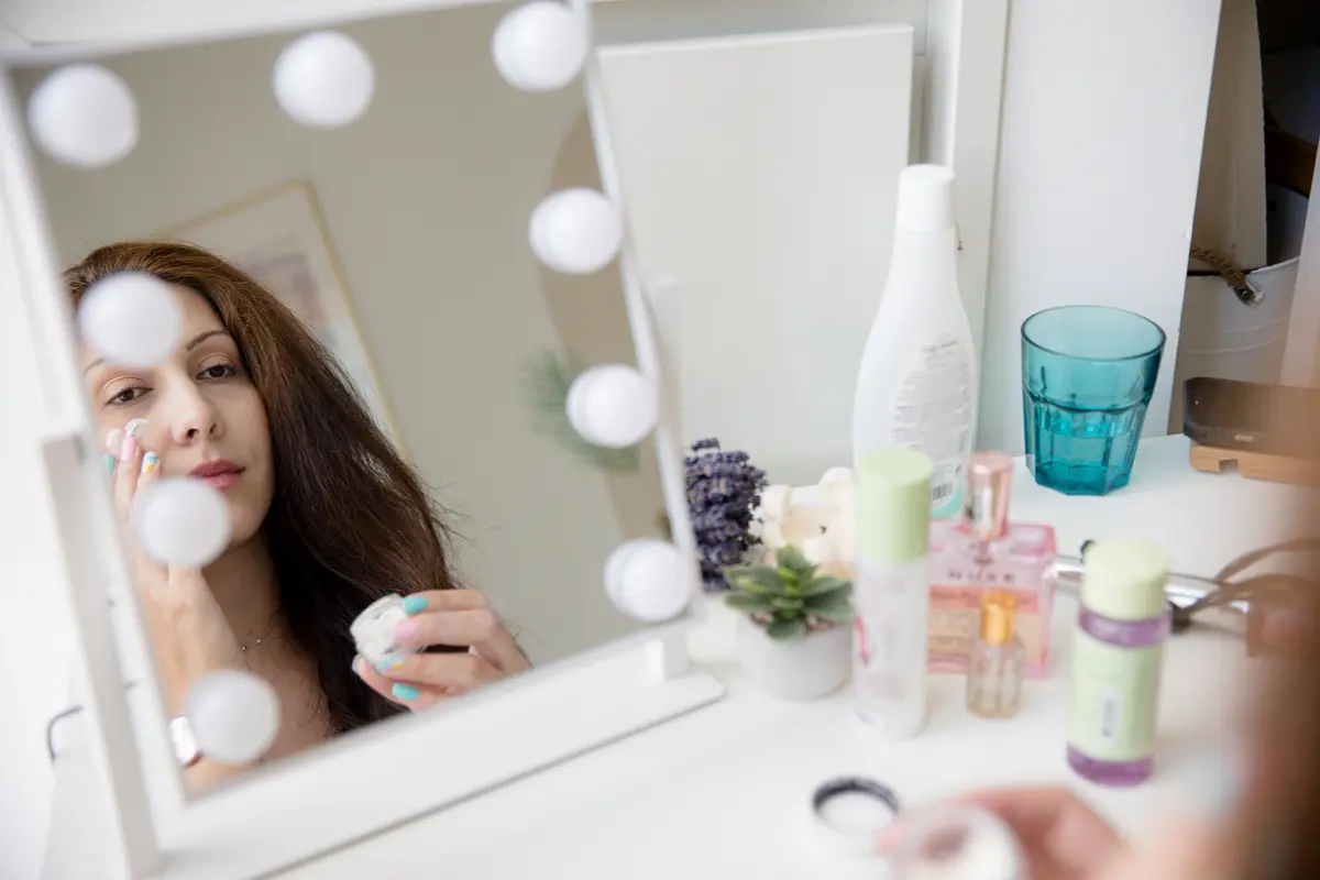 woman applying face cream looking in mirror