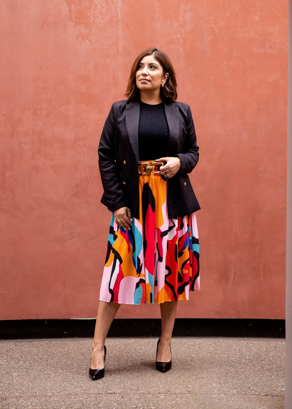 bright colored patterned pleated skirt paired with black blazer, top and pumps