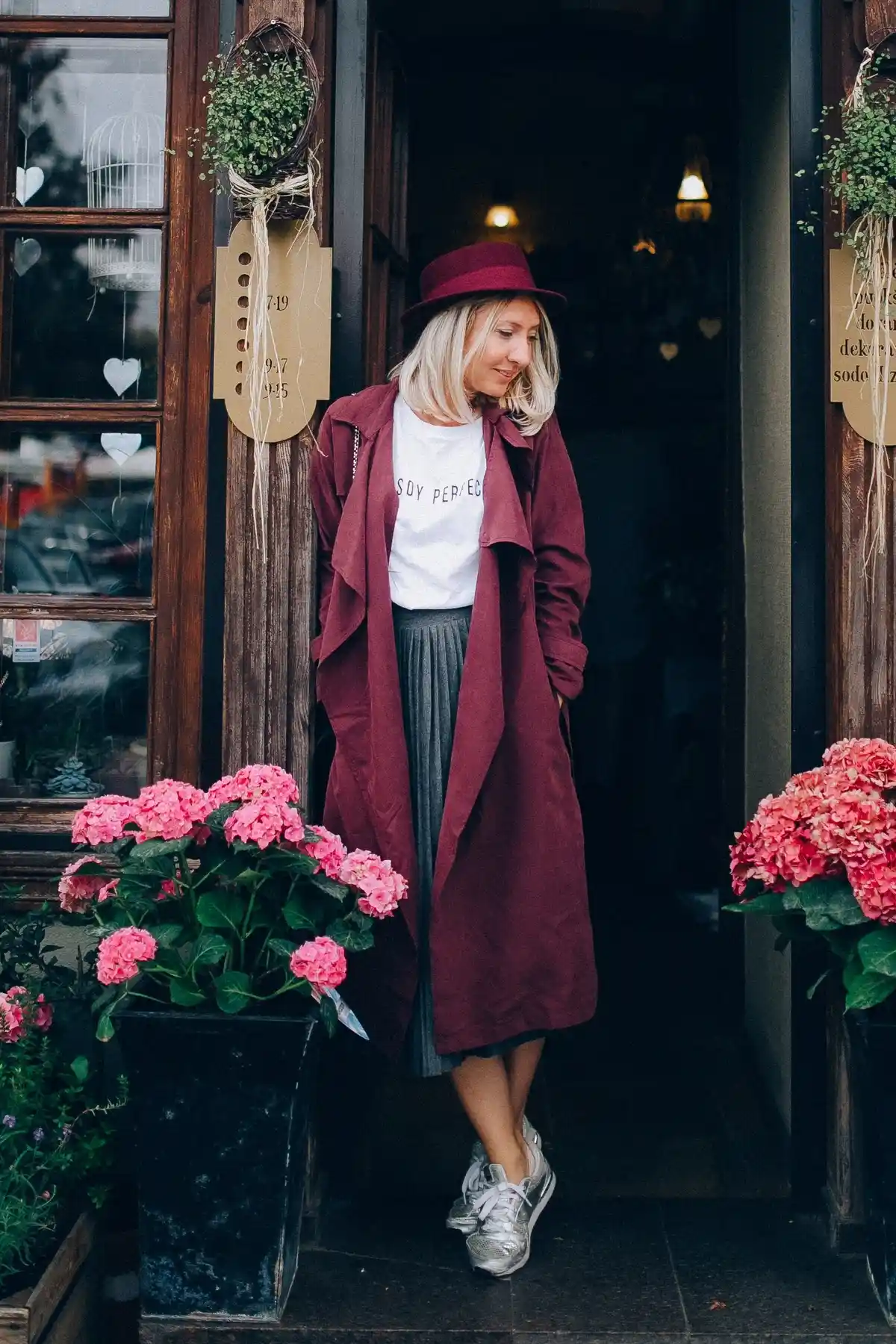 dark grey pleated skirt paired with white t-shirt silver sneakers raspberry coat and hat with brim (1)