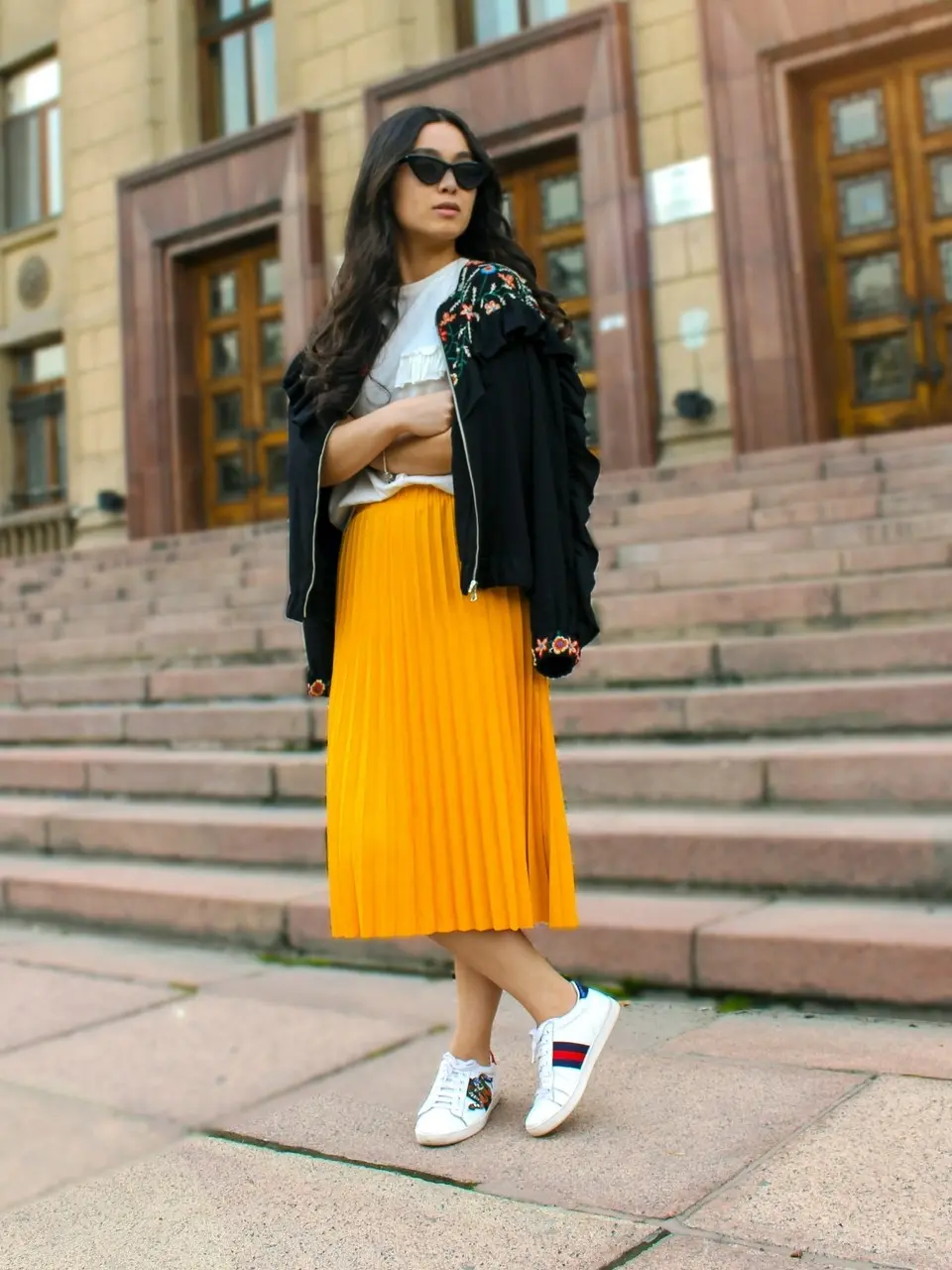 yellow long pleated skirt paired with black bomber jacket and white sneakers
