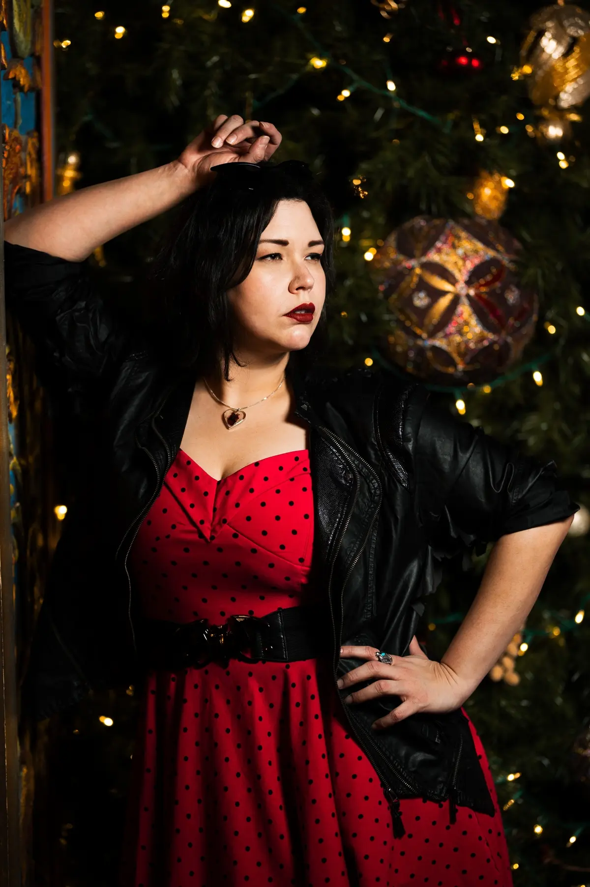 plus size woman wearing red and black polka dot dress matched with black leather jacket and belt