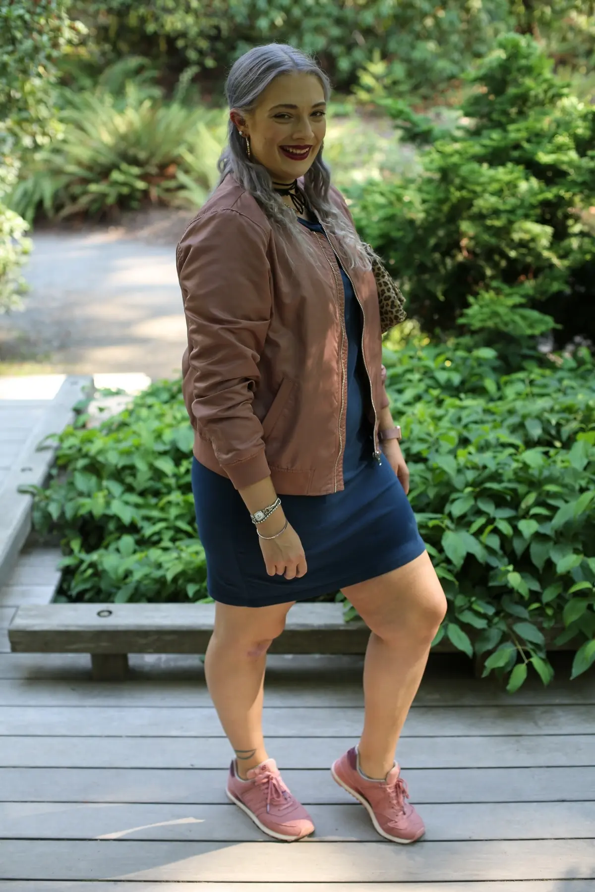 curvy woman wearing dark blue dress paired with sneakers and leather jacket