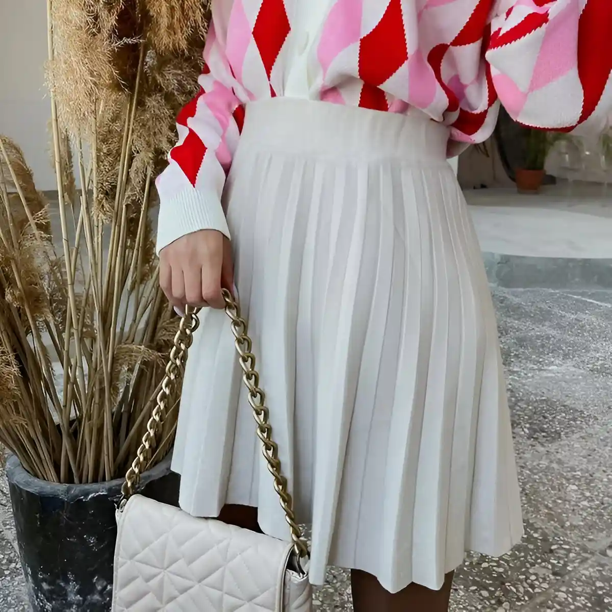 white pleated skirt paired with patterned pink and red cardigan